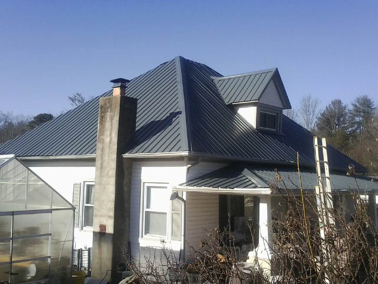 Dark blue standing seam metal roof on a white farmhouse with dormer — Slate & Tile Roof Repair by Roofing Brothers in Aneta