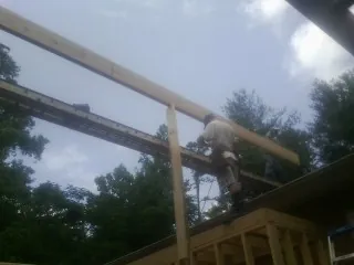 Carpenter setting a ridge beam over a new addition frame — Ice Dam Removal by Roofing Brothers in Aneta