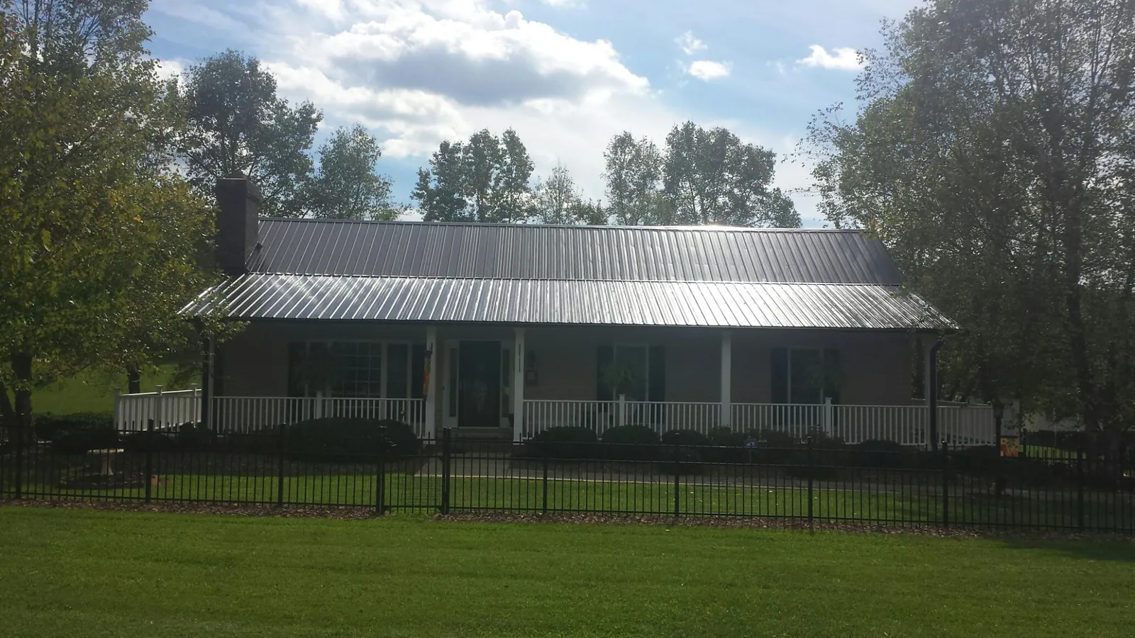 Gray metal roof on a brick ranch with a full width front porch — Gutter Guard Installation work by our crew in Aneta