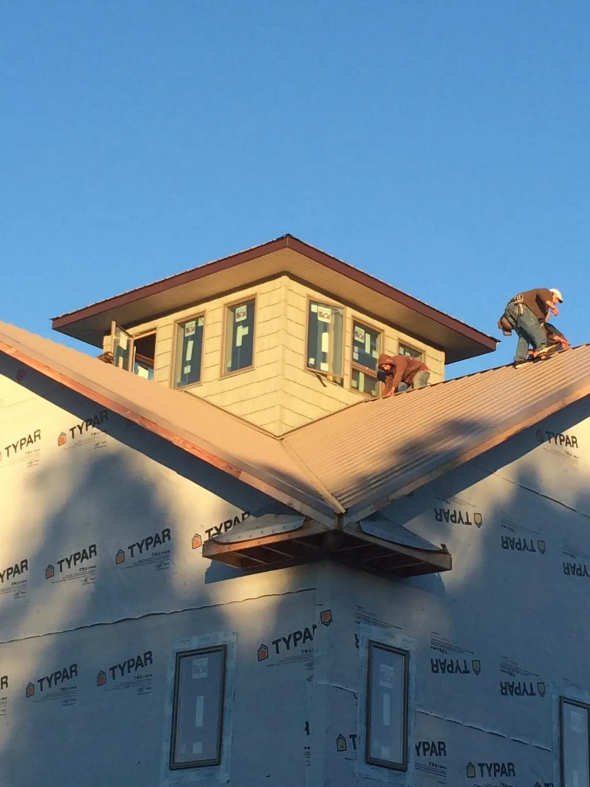 Roofers working around a rooftop cupola on a new metal roof at sunset — Roof Waterproofing in Aneta by Roofing Brothers